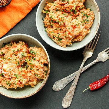 Two bowls of food with two forks on a table