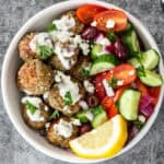 Greek chicken meatballs and Greek salad in a white bowl.