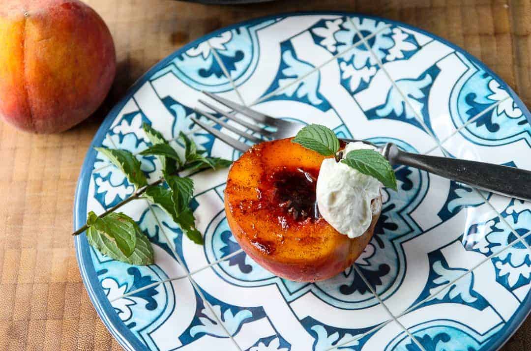 Half of a peach on a plate with whipped cream