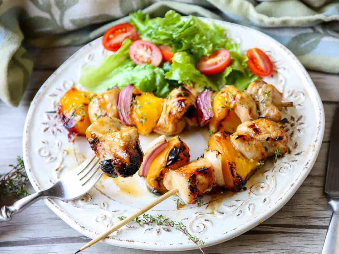 A plate of food on a table, with chicken and peaches