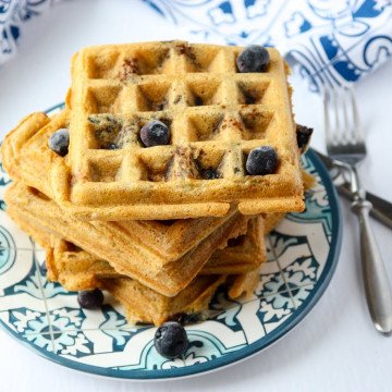 A stack of waffles on a plate, with blueberries