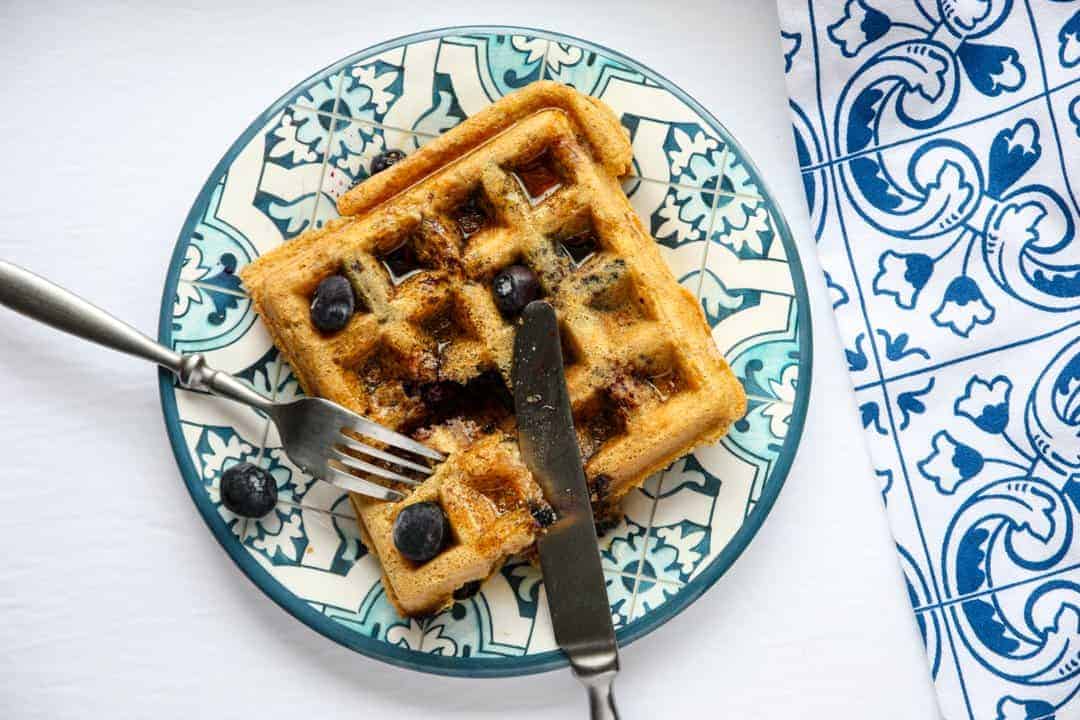 A waffle on a plate with a knife and fork