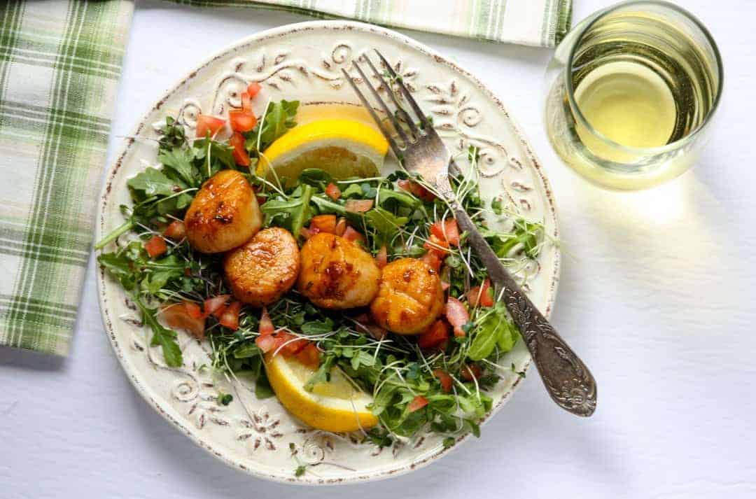 A plate of food on a table, with Scallops and Chardonnay