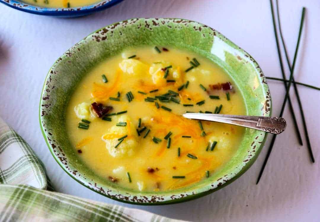Soup in a green bowl with a silver spoon.