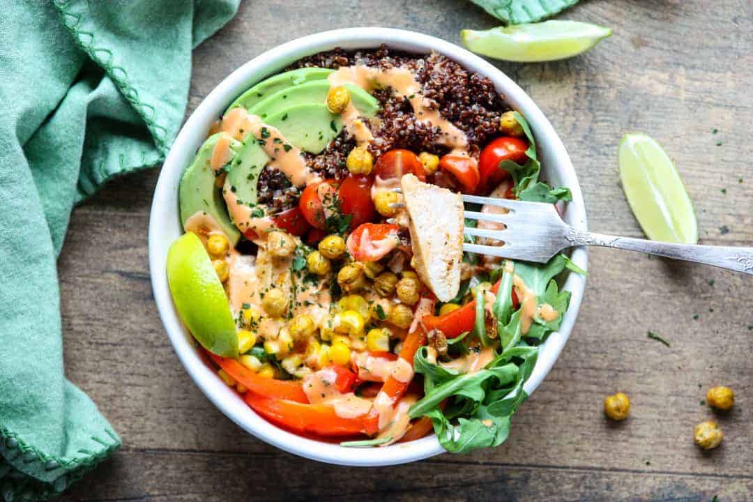 Burrito ingredients in white bowl with fork on wooden table