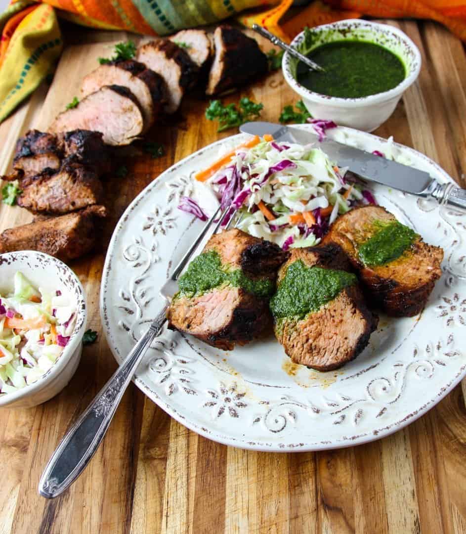 A plate of food on a wooden table, with Pork tenderloin