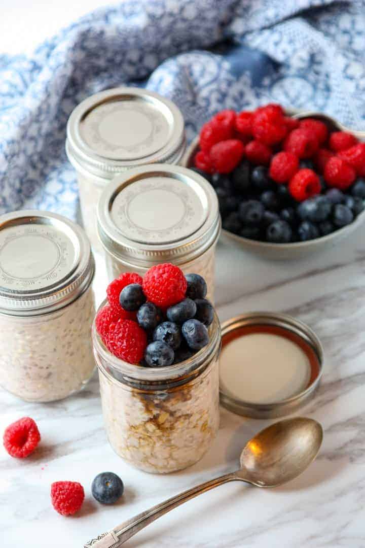 4 jars of overnight oats, 3 with lids and one topped with berries