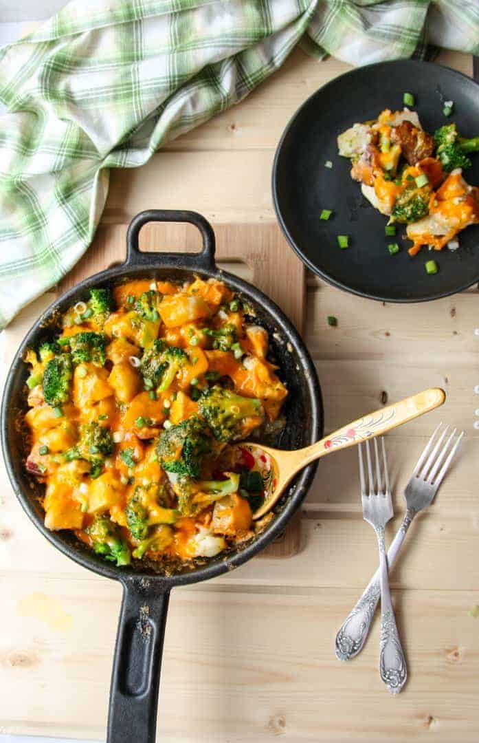 Cheese, broccoli, and potato casserole in black skillet.