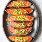six baked sweet potato halves on a black cast iron skillet