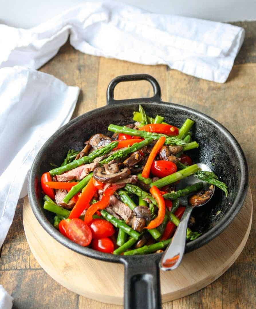A cast-iron skillet with meat and vegetables