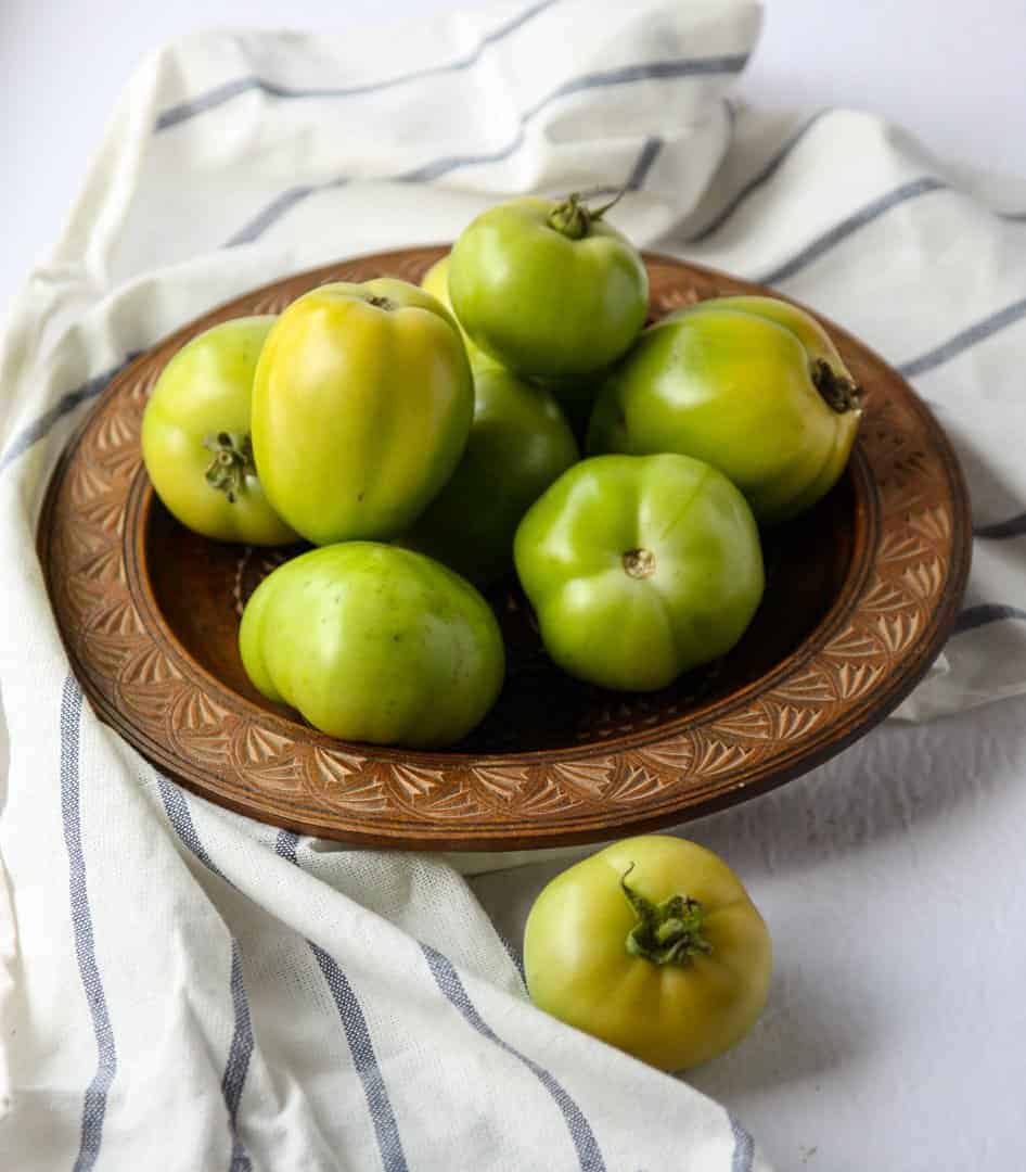 Green tomatoes in a wooden bowl on a table
