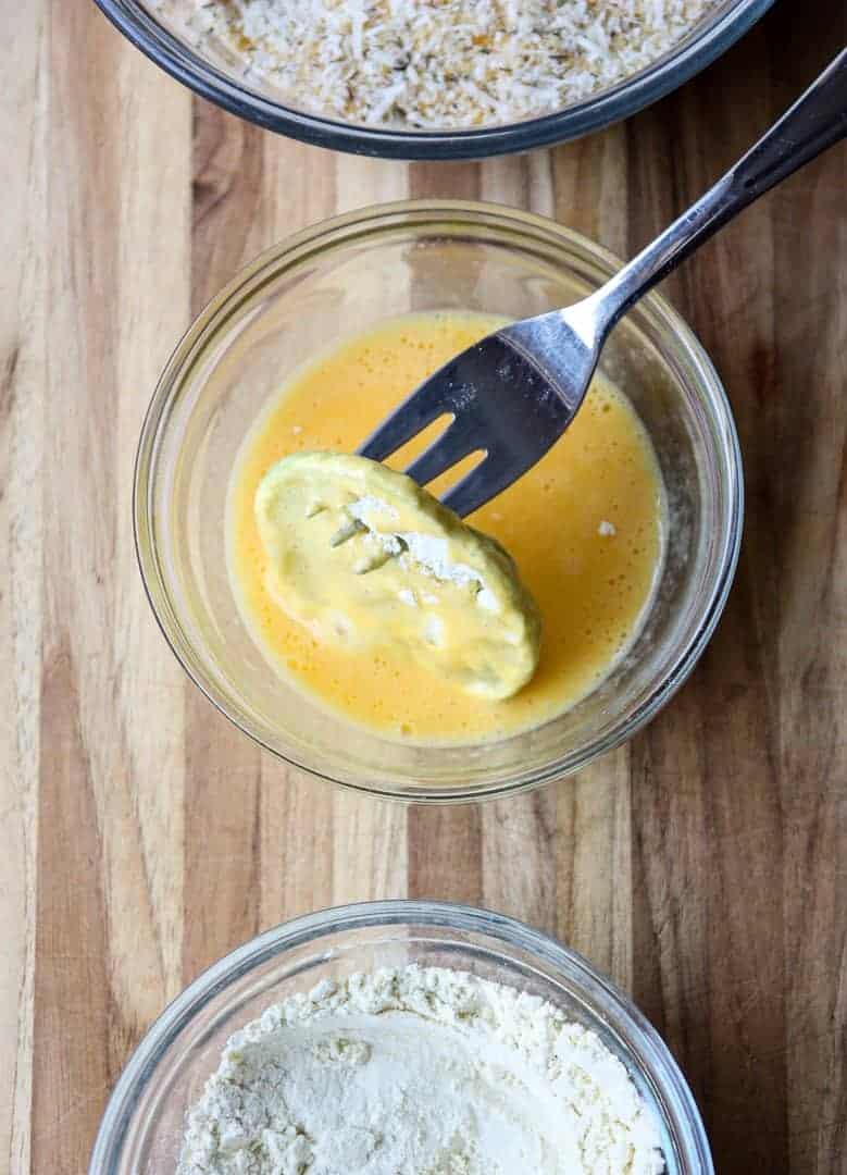 Dipping flour-dredged green tomato slice in beaten egg