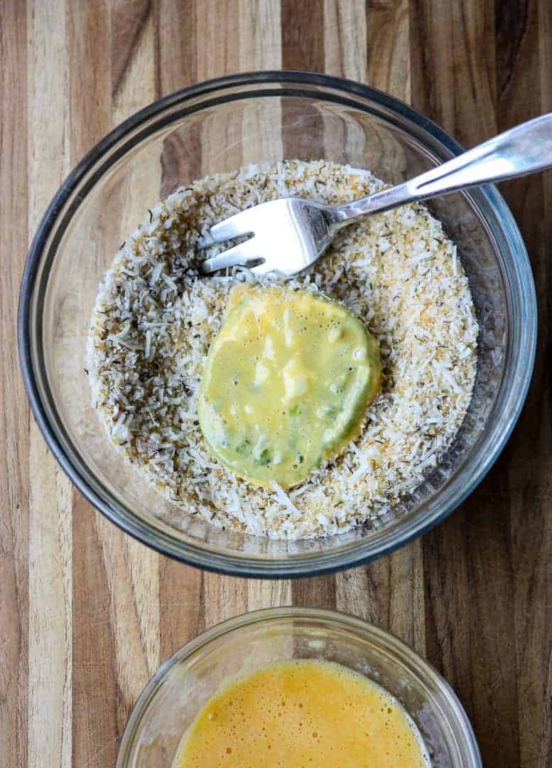 Coating green tomato slices in bread crumbs
