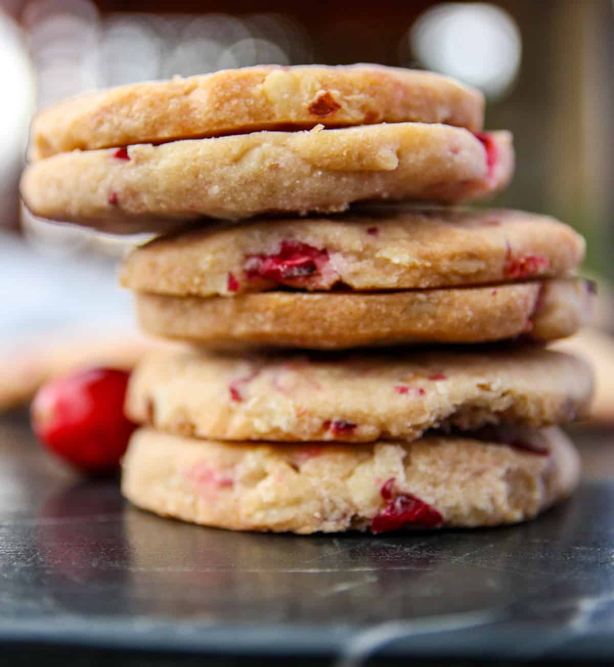 A stack of cranberry walnut shortbread cookies on a marble countertop.