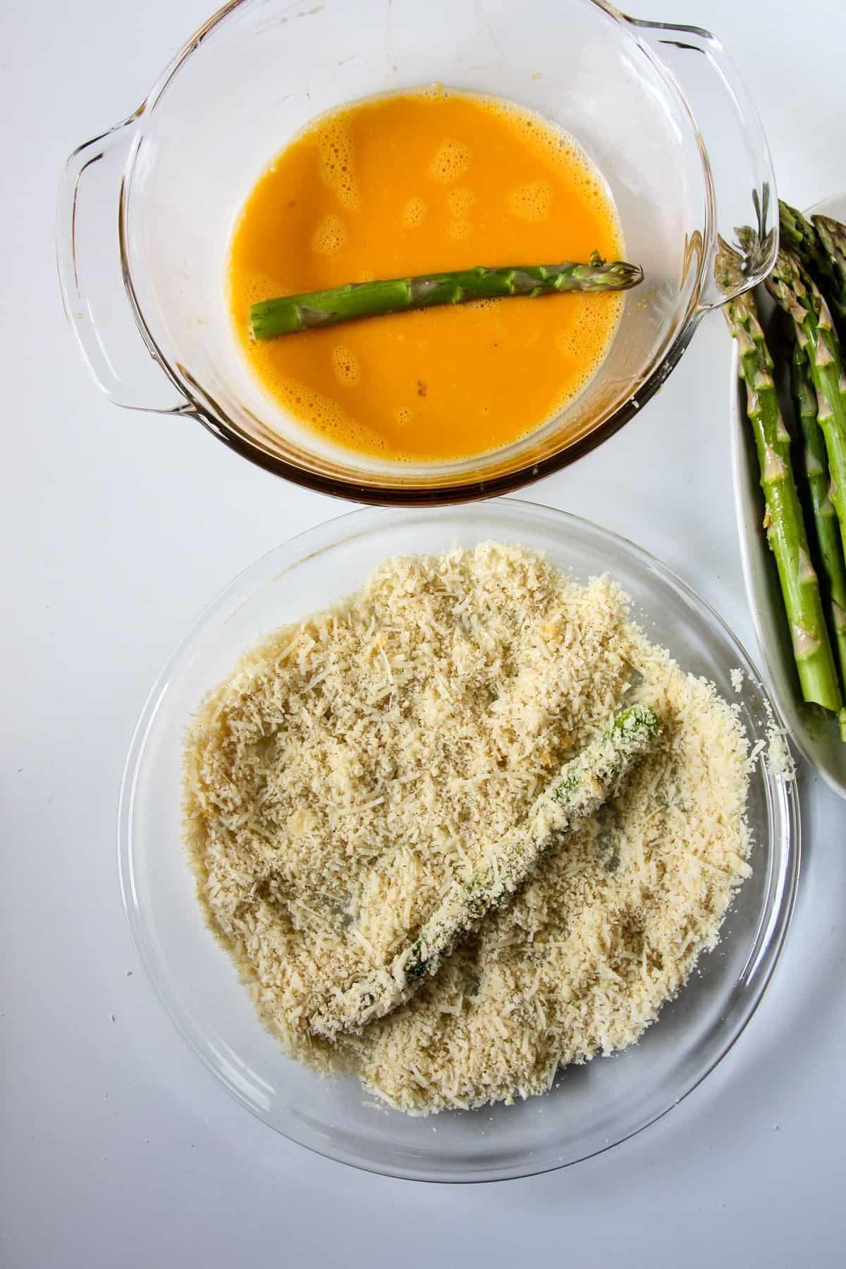 Egg coated spears being rolled in crumb mixture.