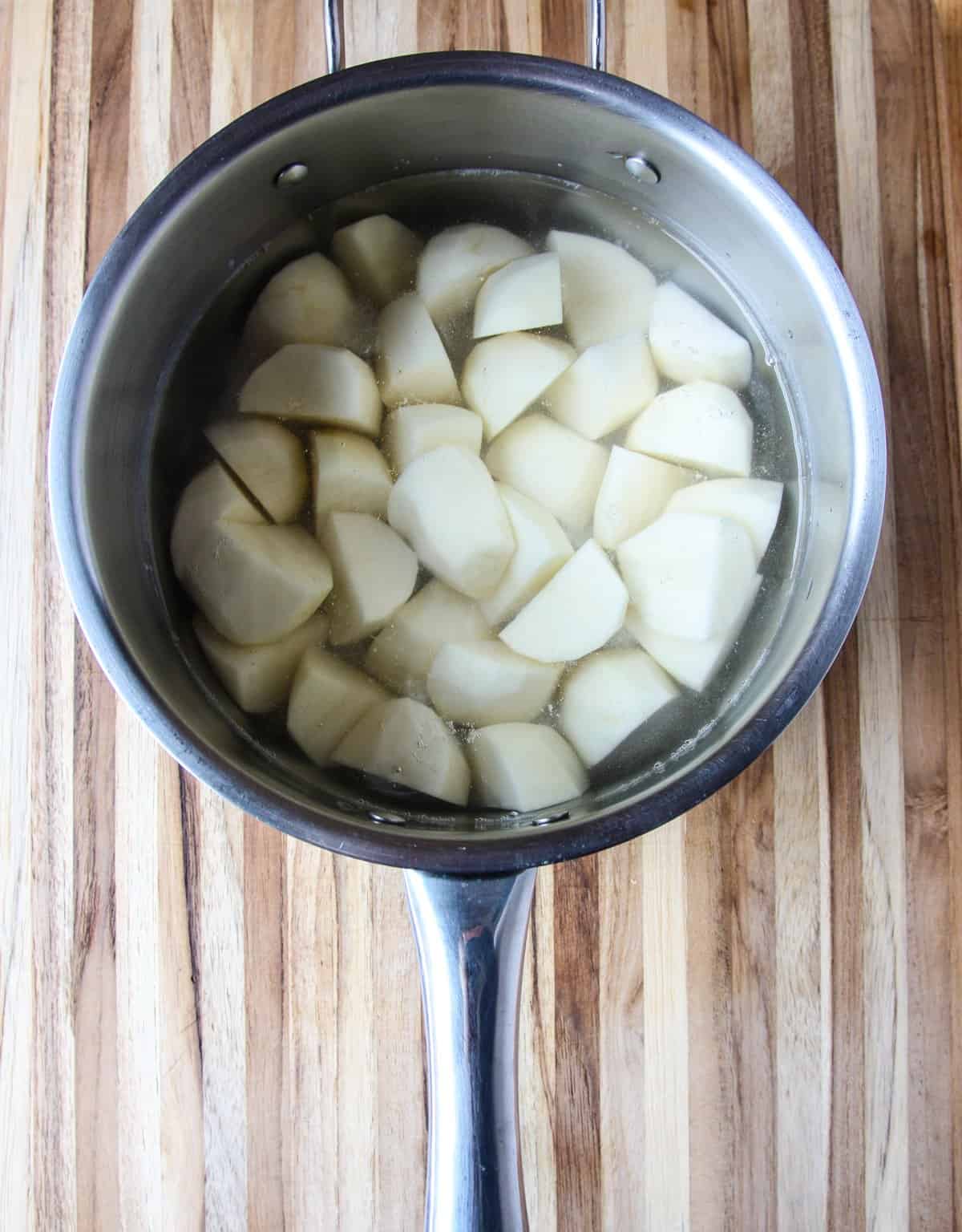 Cut raw potatoes in a saucepan covered in water.