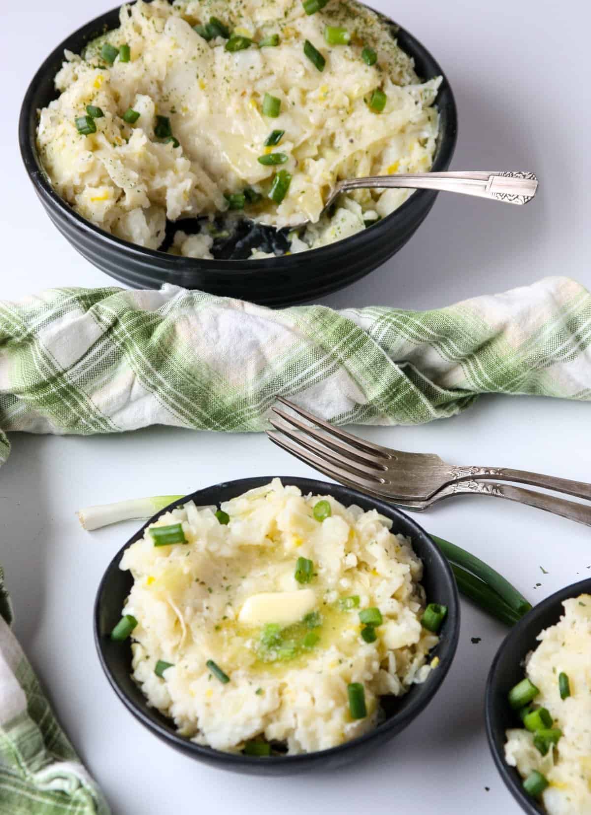 Mashed Potatoes in three black bowls on a white table.