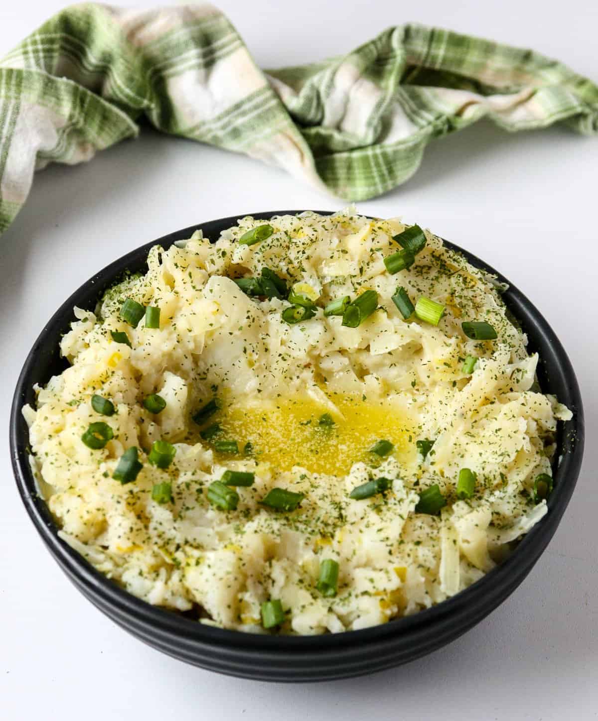 A bowl of colcannon potatoes topped with melted butter and chopped scallions.