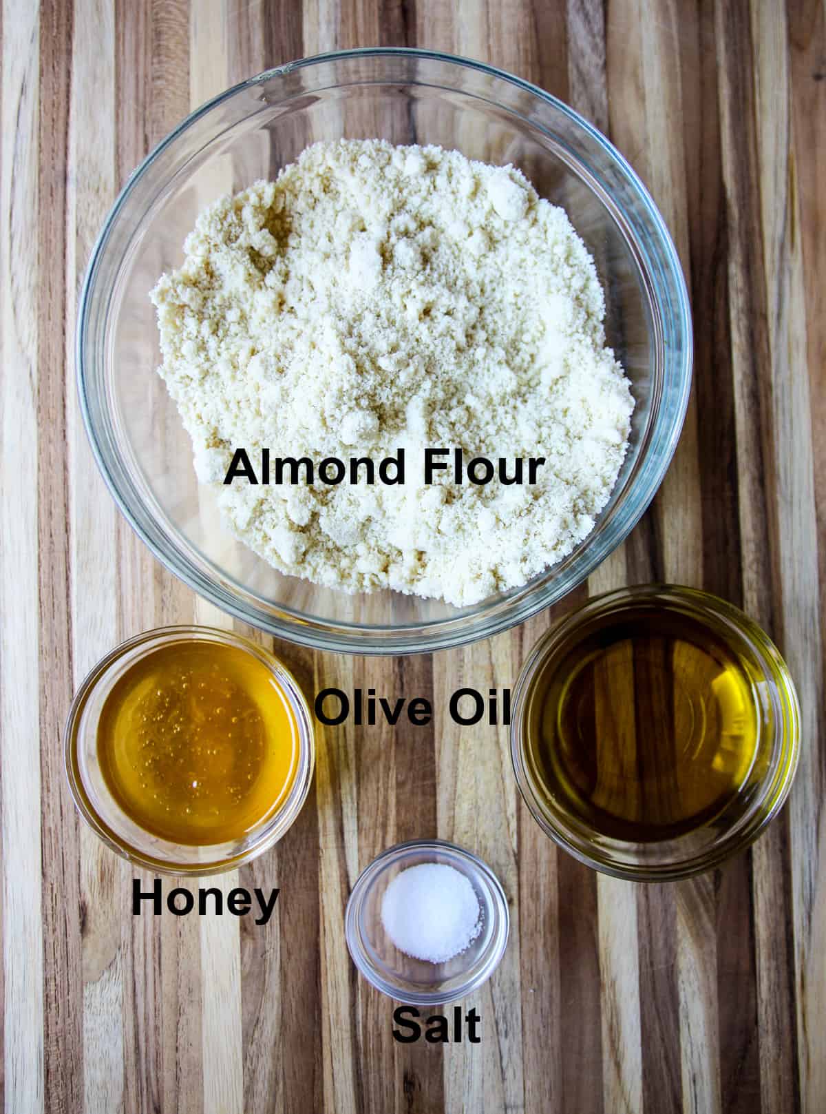 Ingredients for the tart shell in glass bowls on a wooden board.