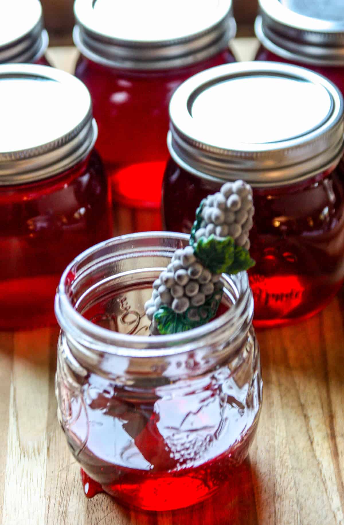 An opened jar of grape jelly on a wooden board.