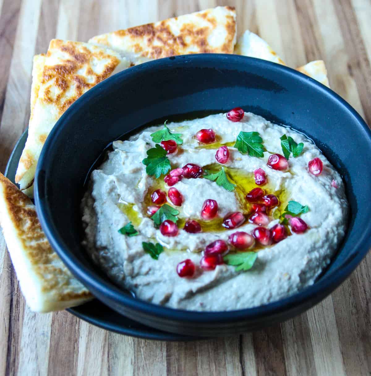 Mutabbal eggplant dip in a black dish, with pita triangles.