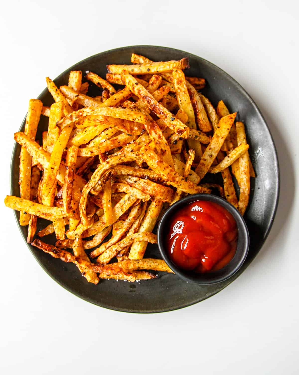 A plate of rutabaga fries with a small dish of ketchup.