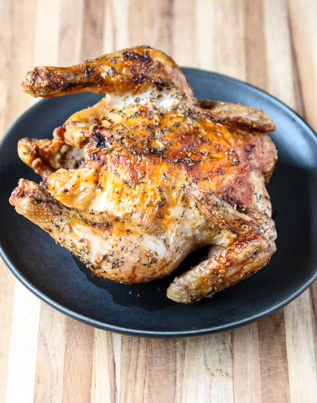 An air-fried Cornish hen on a black plate.