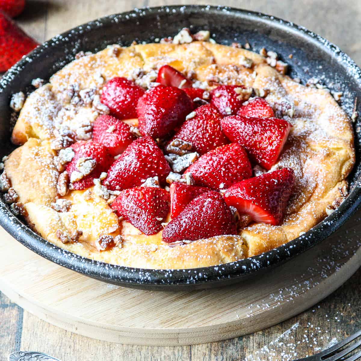 A strawberry filled Dutch baby pancake in a skillet.