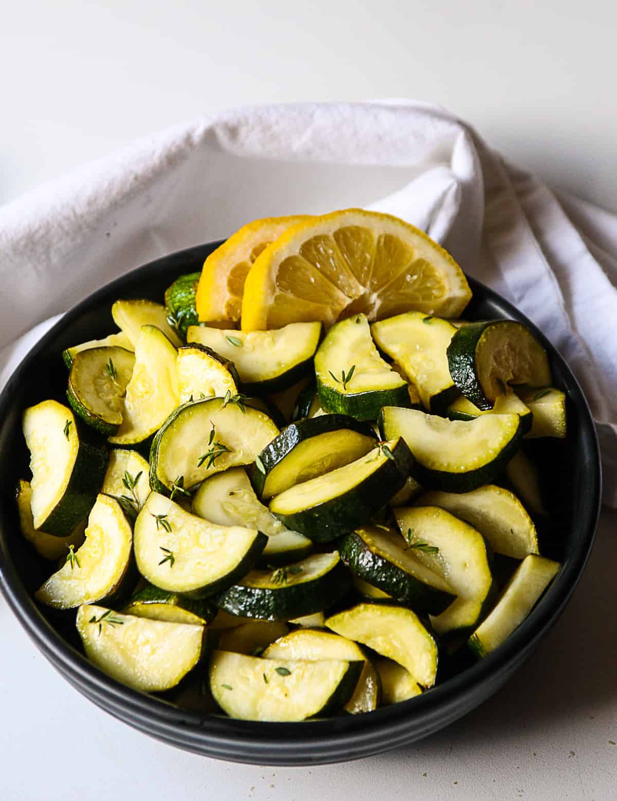 A black bowl filled with air fried zucchini slices.