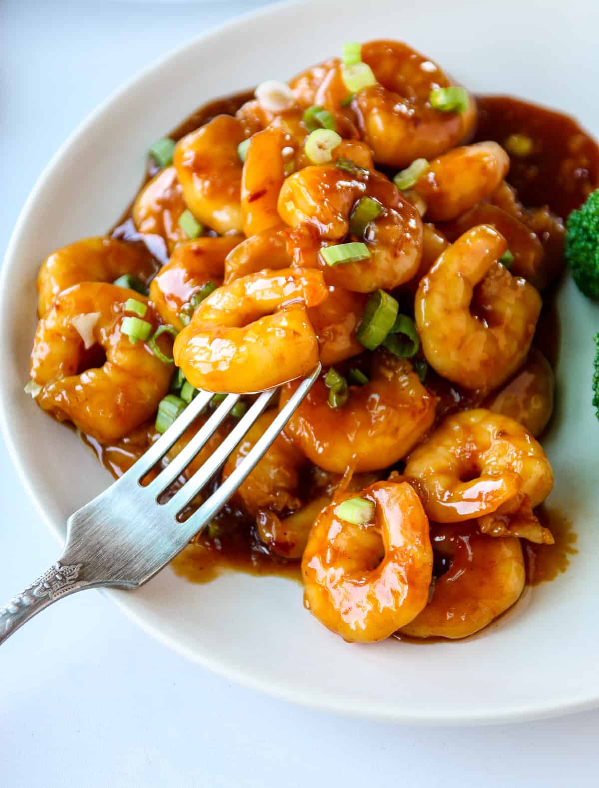 A silver fork in a plate of general tso shrimp.