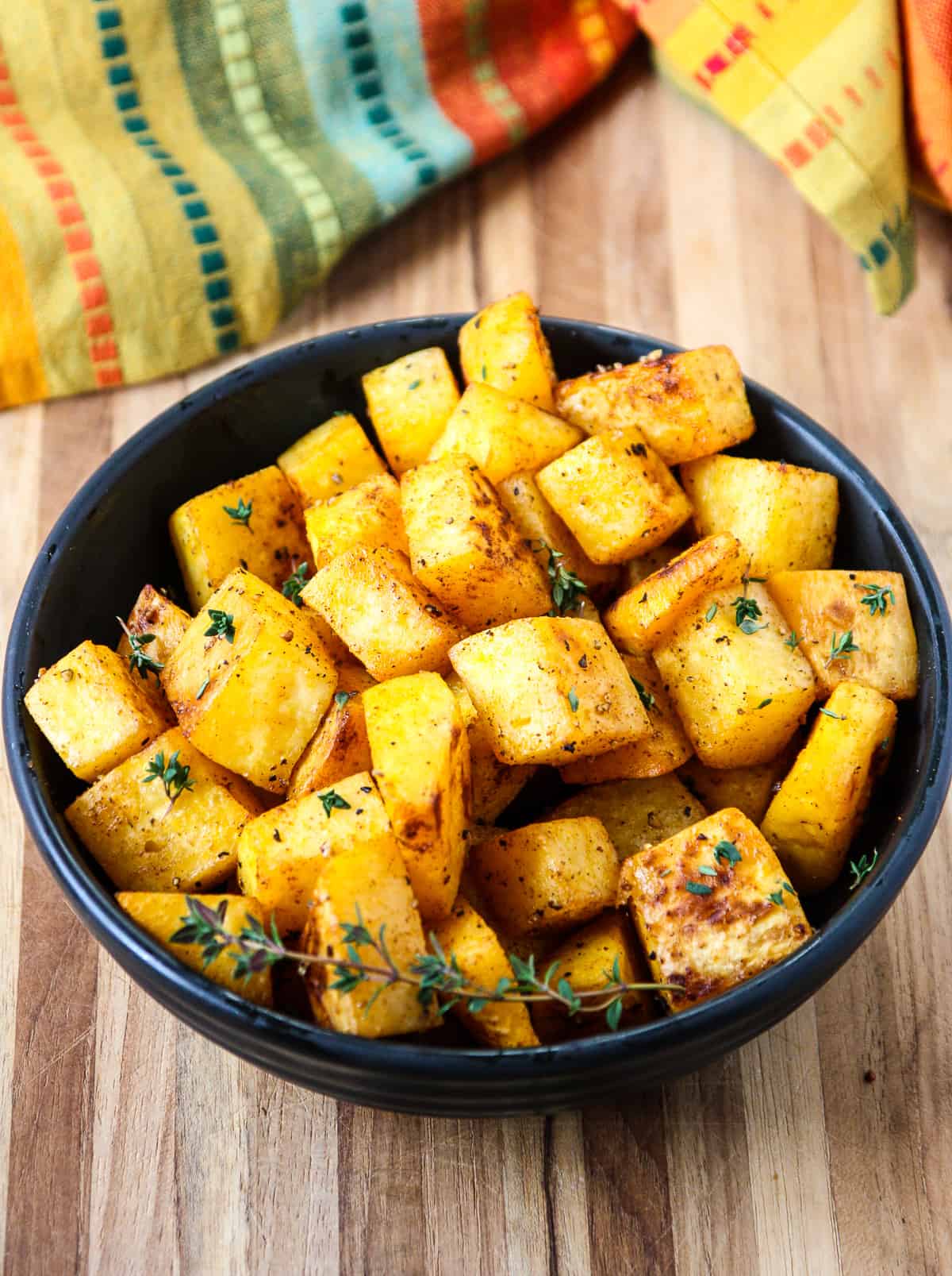 A bowl of the roasted cubes garnished with a sprig of fresh thyme.
