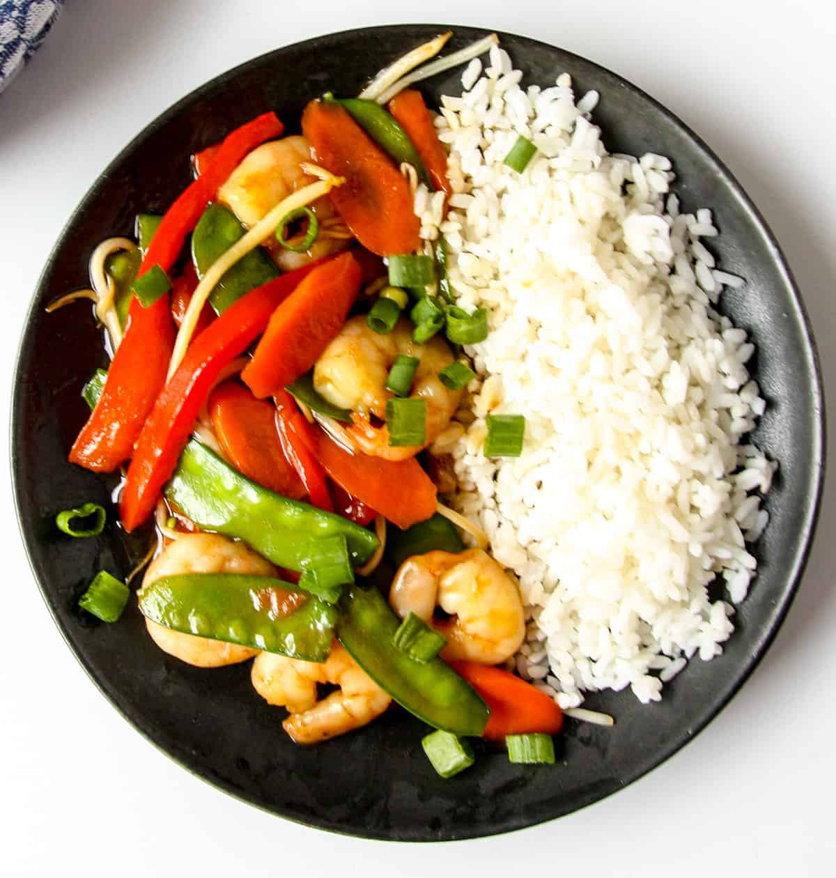 Shrimp Chop Suey and a side of rice on a black plate.