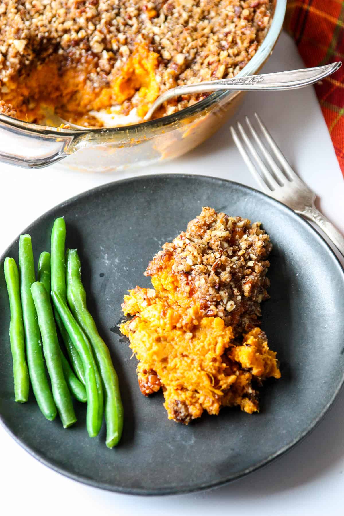 A serving of sweet potato crunch with green beans on a black plate.