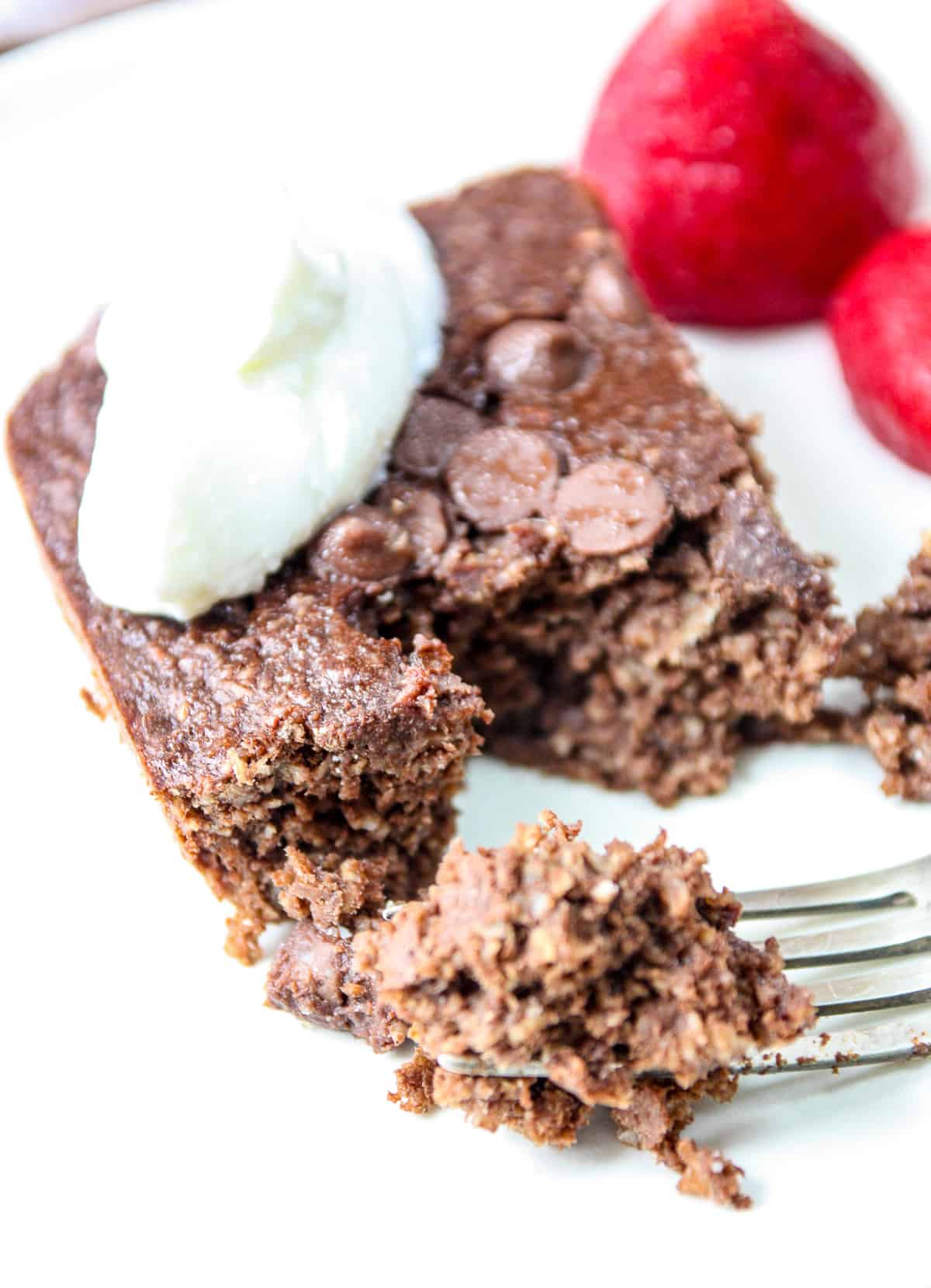 A slice of chocolate oats and strawberries on a plate.