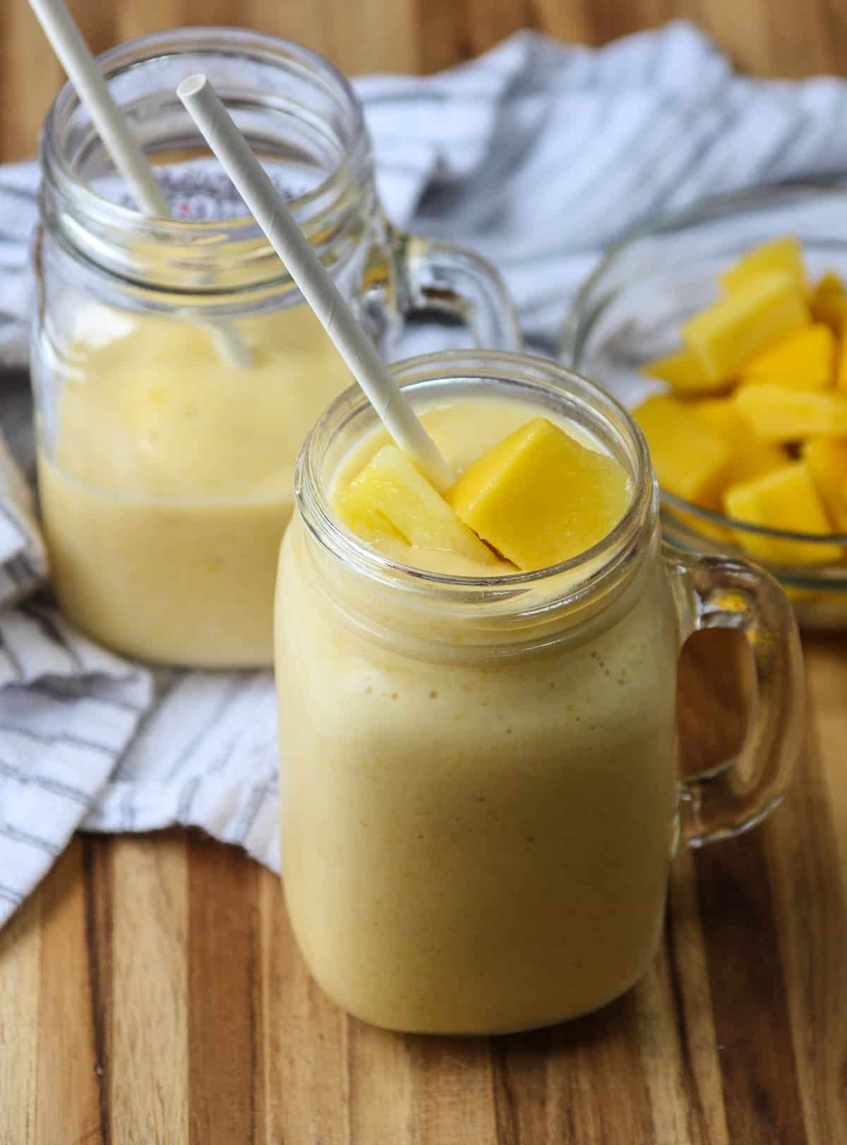 Two servings of mango pineapple smoothie in glass mugs.
