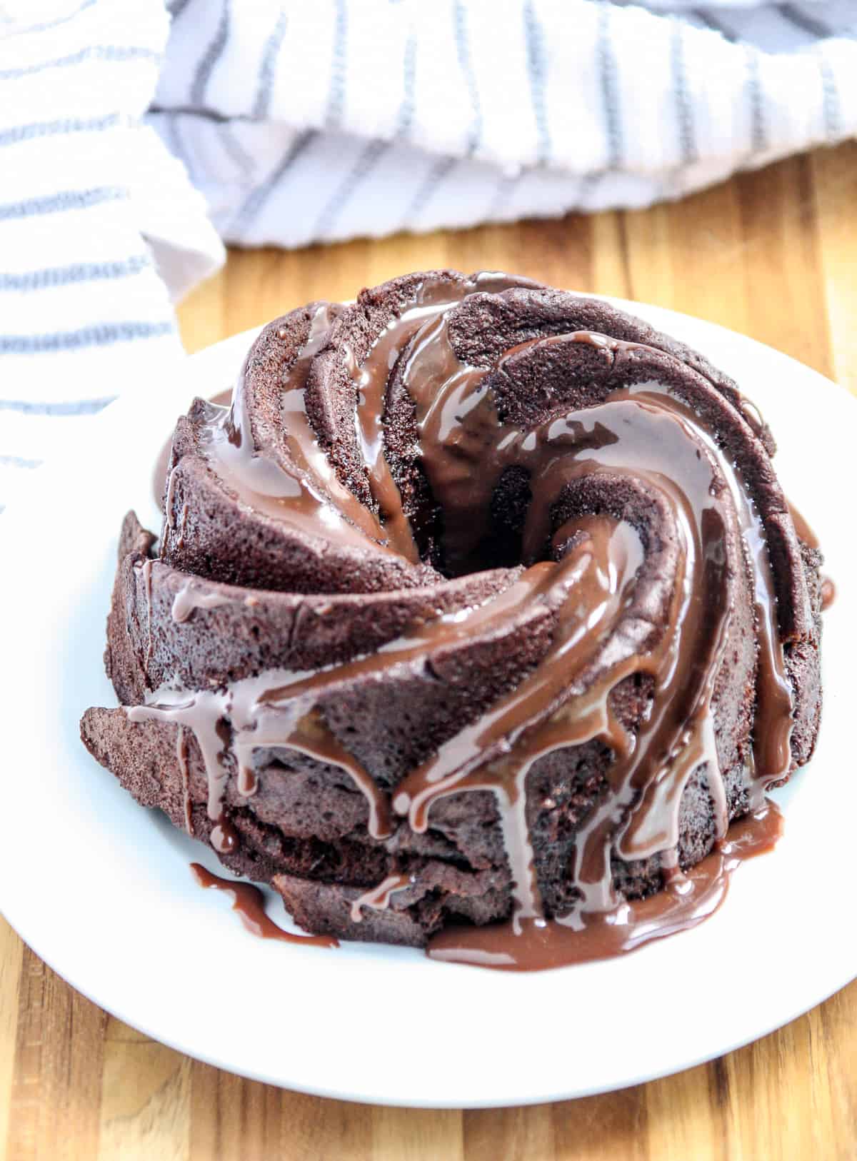 The chocolate cake on a white plate drizzled with chocolate sauce.