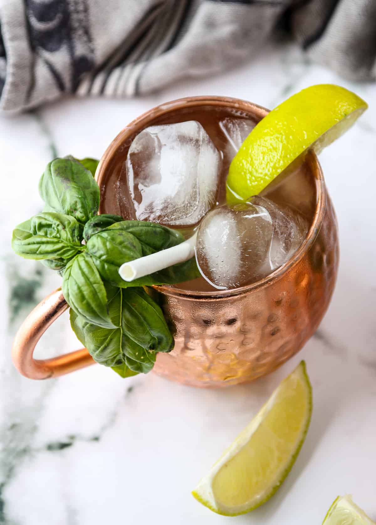 Irish mule drink in a copper cup with ice , garnished with a basil sprig.