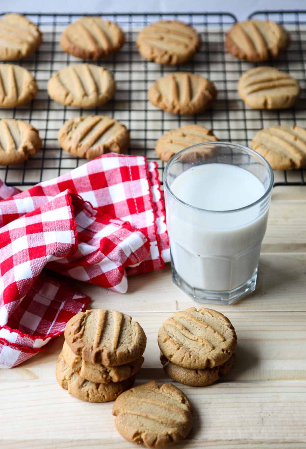 Two stacks of cookies and a glass of milk on a wooden table.