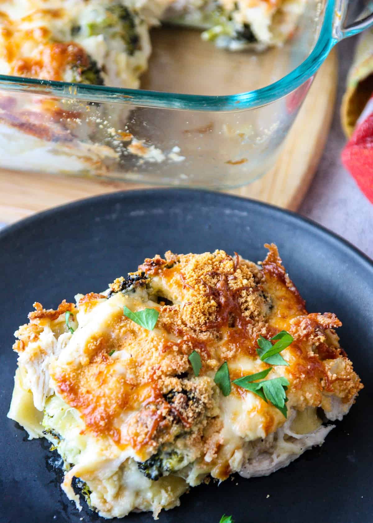 A slice of lasagna on a black plate.
