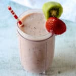 Kiwi quencher tropical smoothie in a tall glass with a pink and white straw.