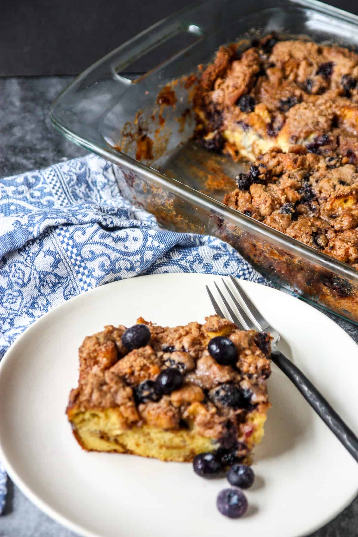 A slice of brioche French toast casserole on a white plate with a black fork.