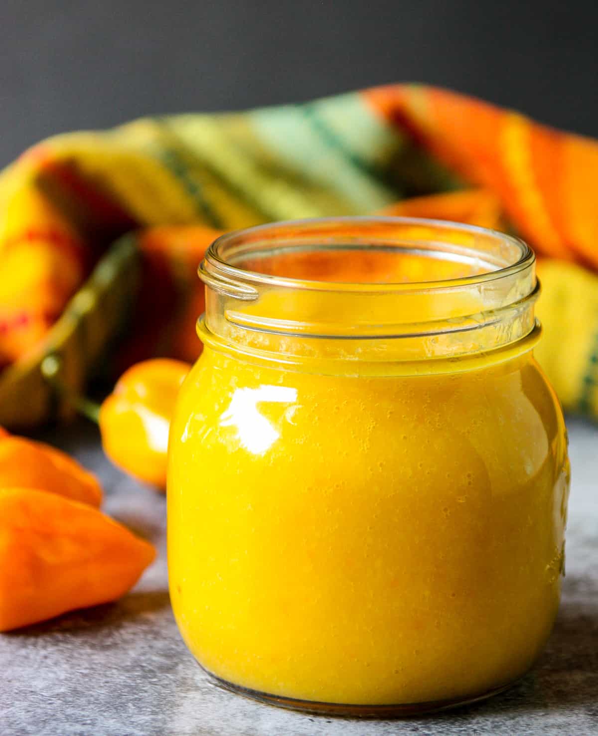 Bright yellow mango habanero hot sauce in a glass jar.