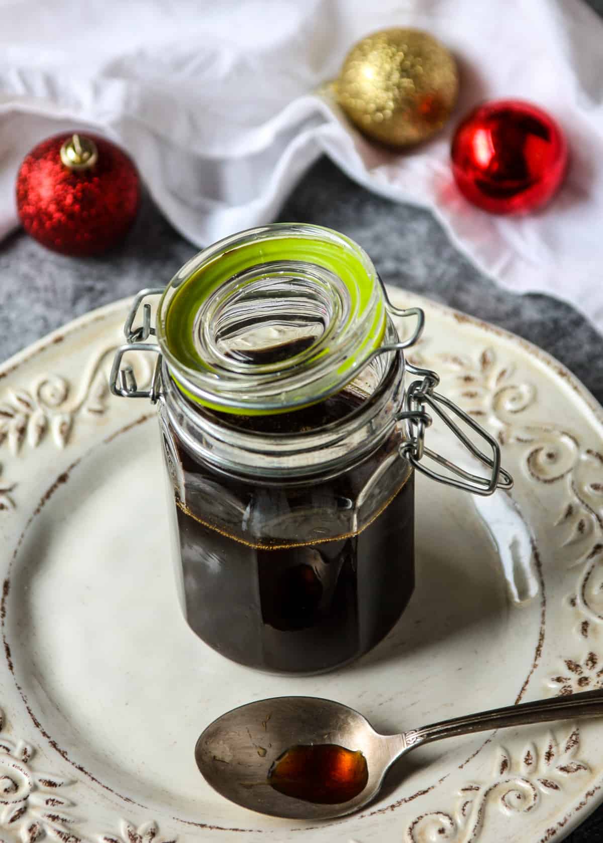 Gingerbread syrup in a glass jar with a half opened hinged lid.