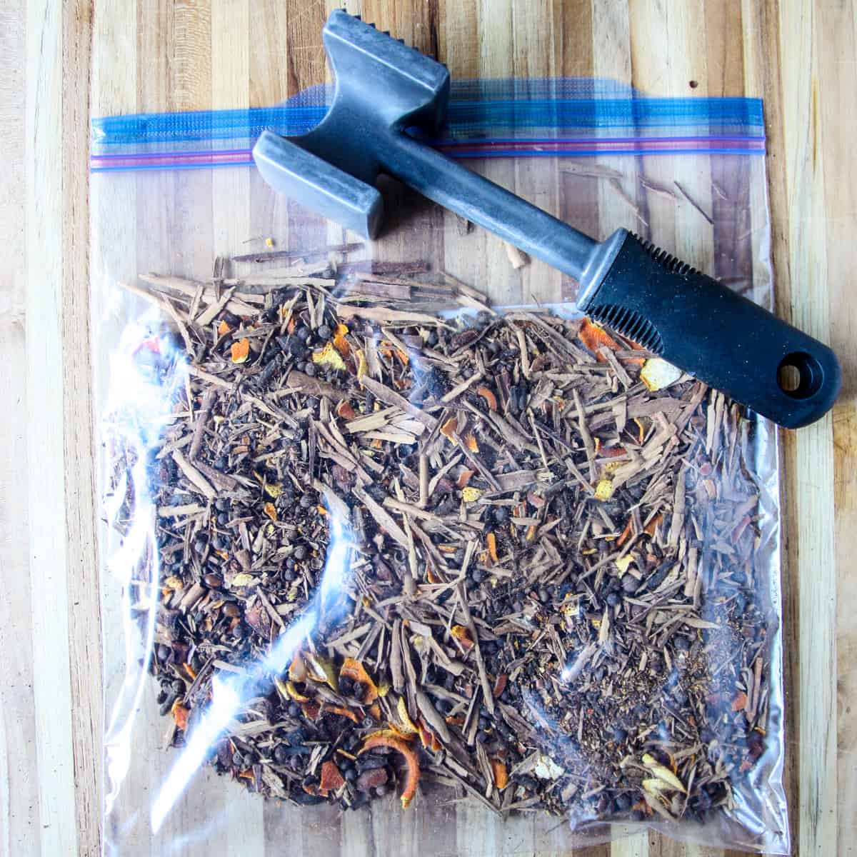 Spices in a plastic bag with a meat mallet for crushing.