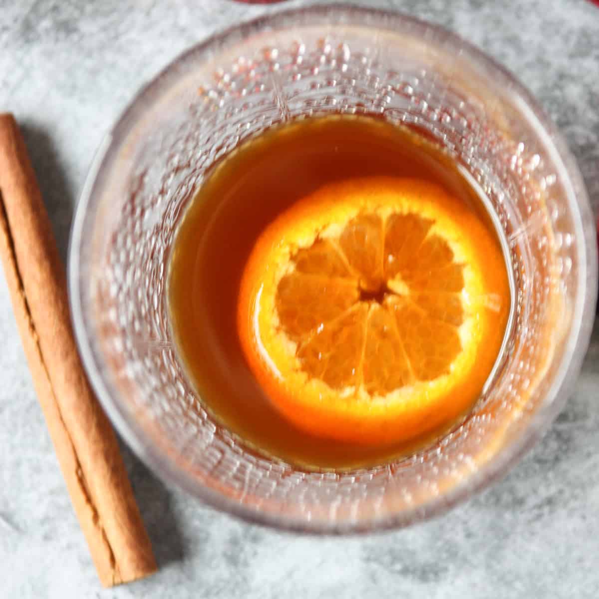 The finished cocktail garnished with an orange slice and a cinnamon stick.