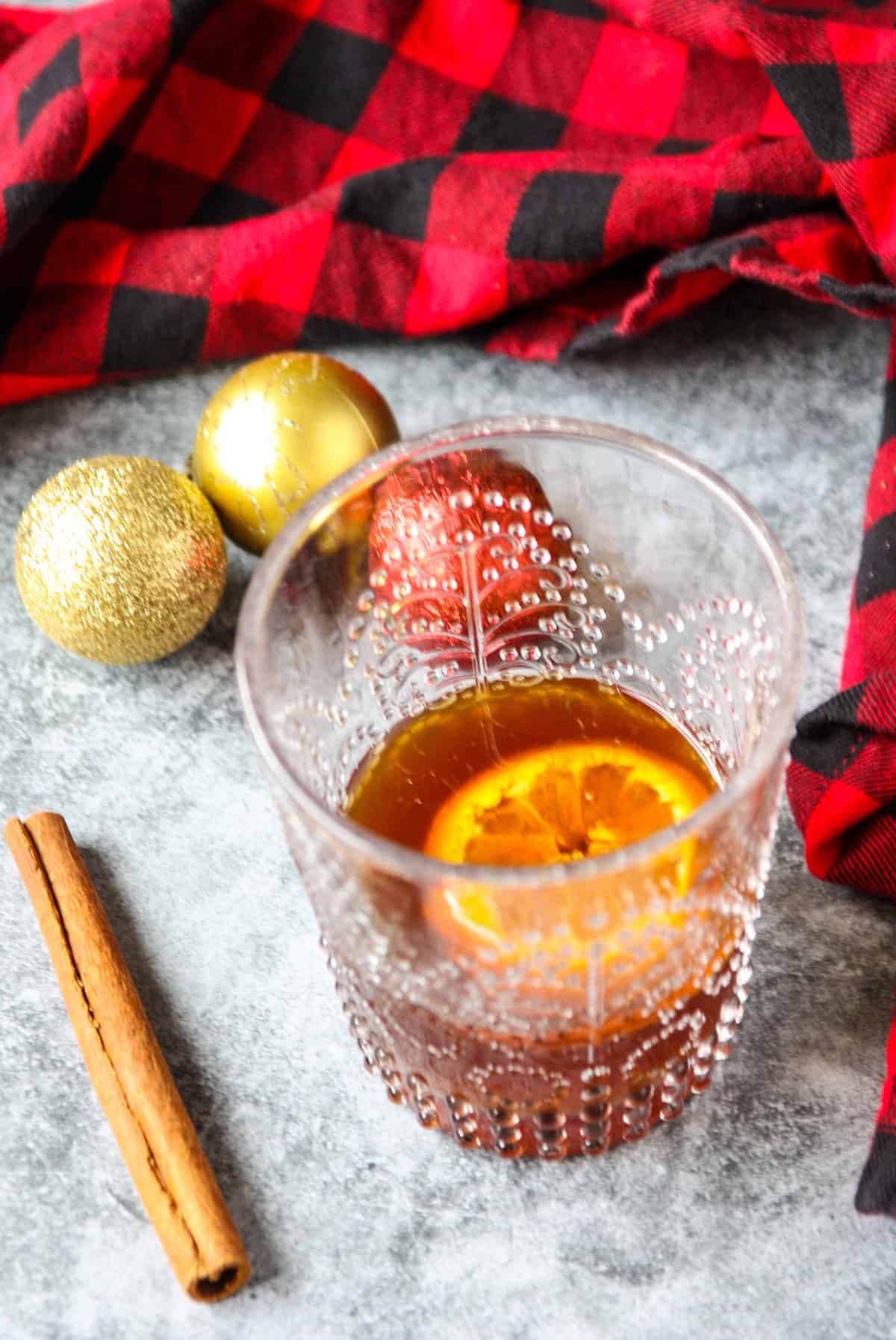 An old fashioned cocktail garnish with an orange slice, and some Christmas tree ornaments.