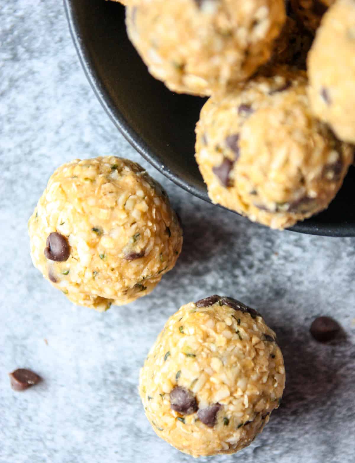 Two oatmeal bites on a stone countertop with a few chocolate chips.