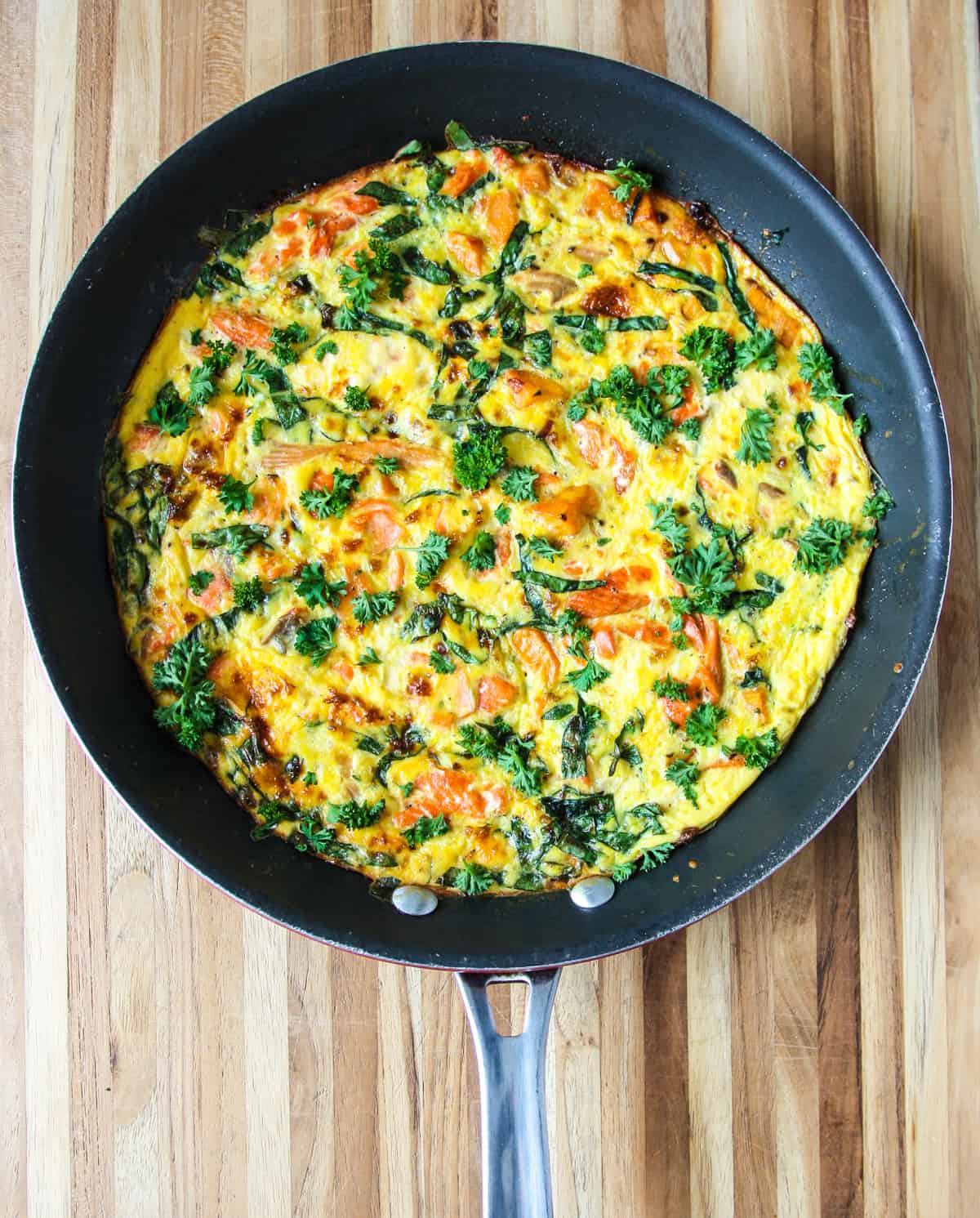 Salmon frittata in a round black skillet.