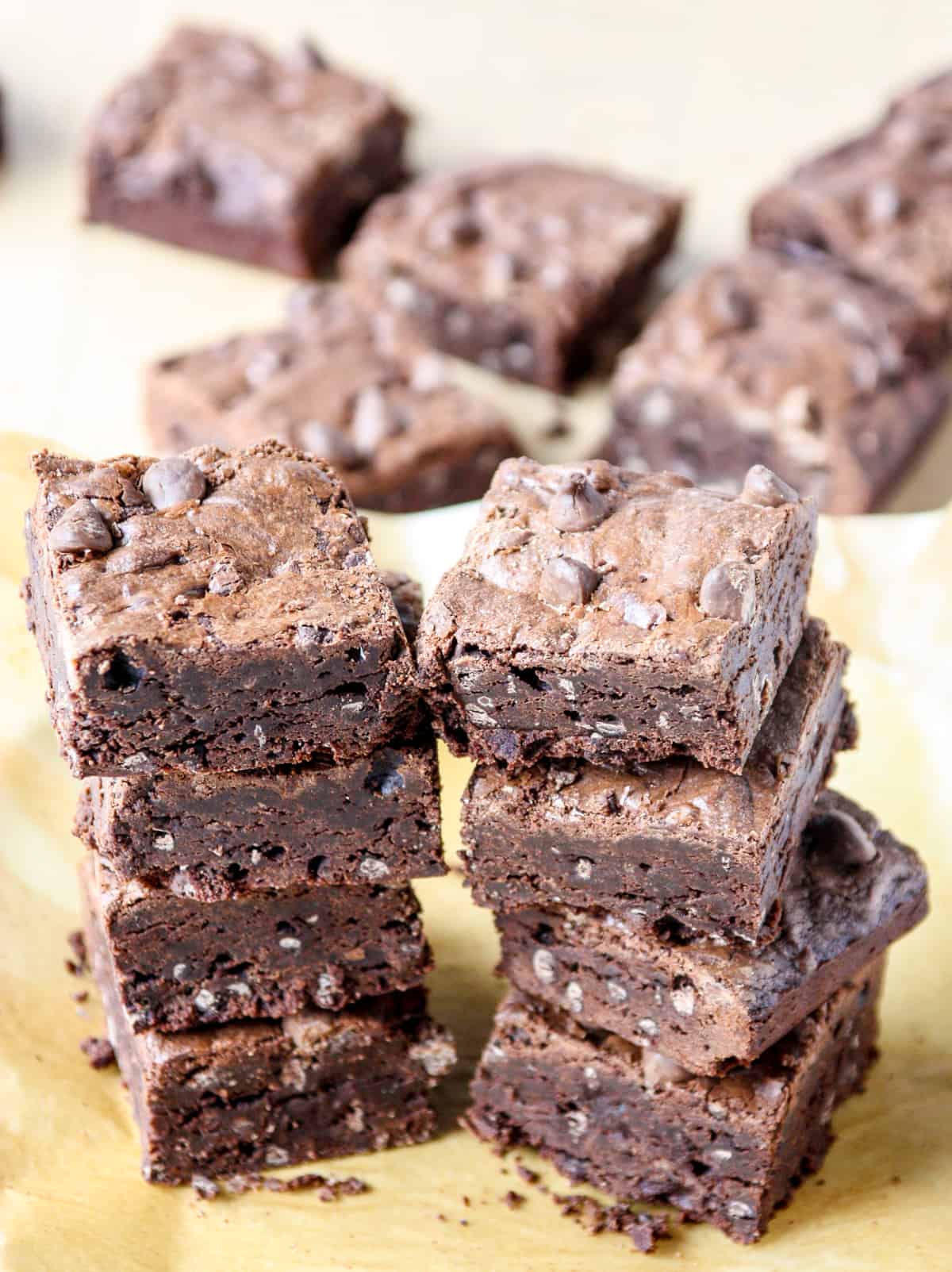 Two stacks of 4 brownies on parchment paper.