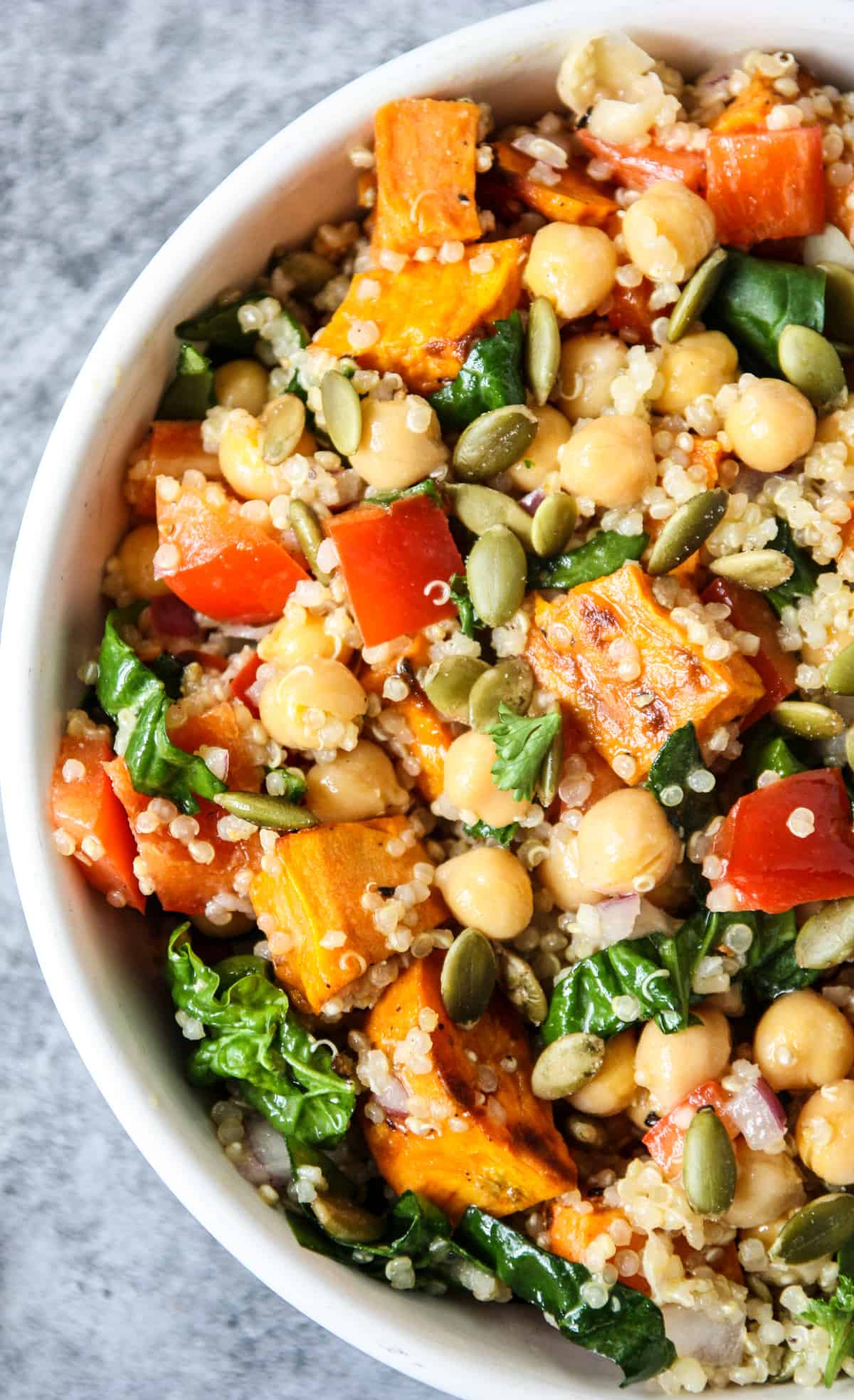 quinoa and sweet potato salad in a white bowl on a stone counter top.